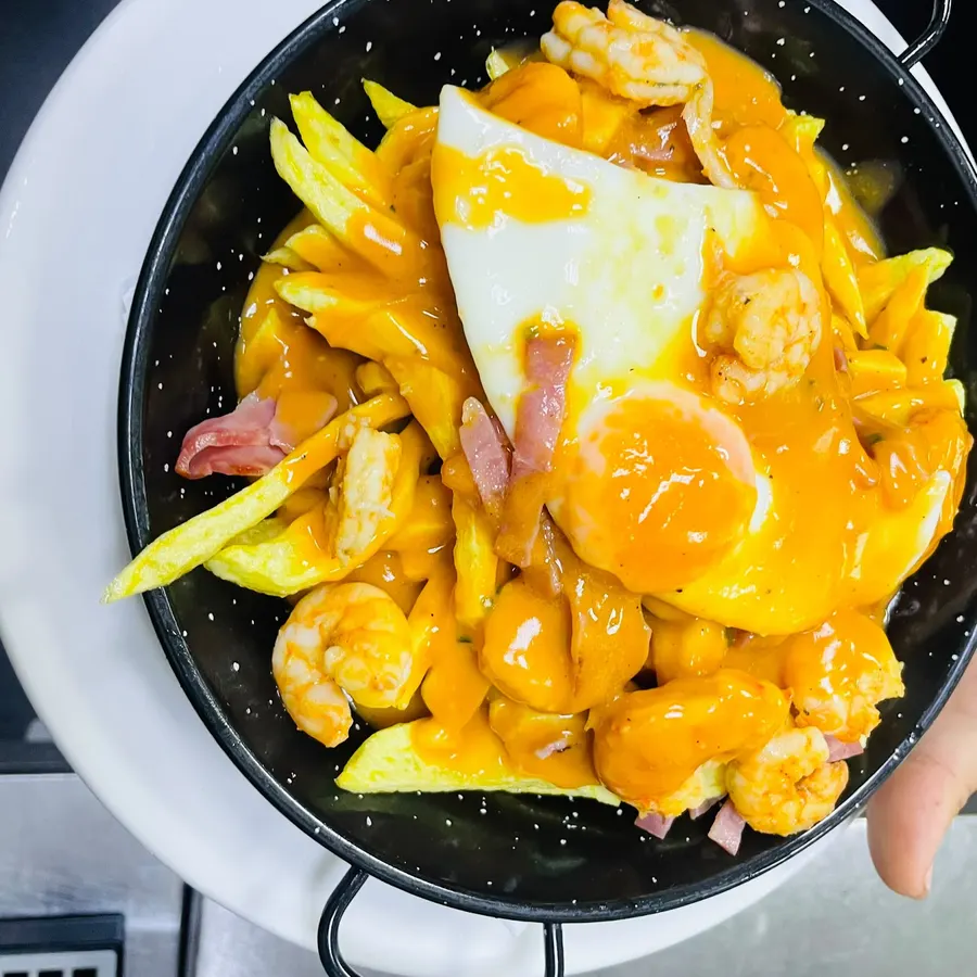 Uma frigideira com batata, ovo, camarão e molho