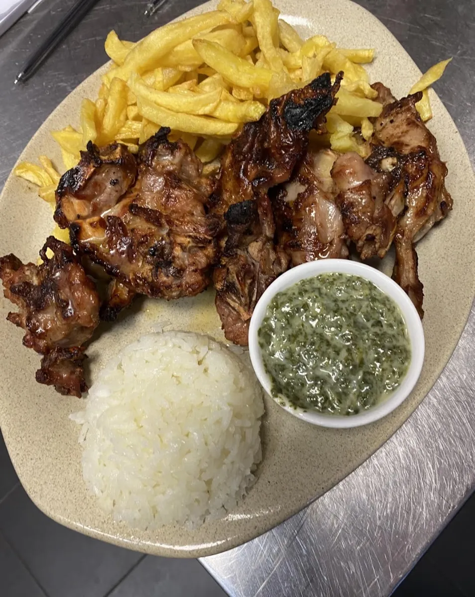 Grelhado com batata frita, arroz e um molho verde