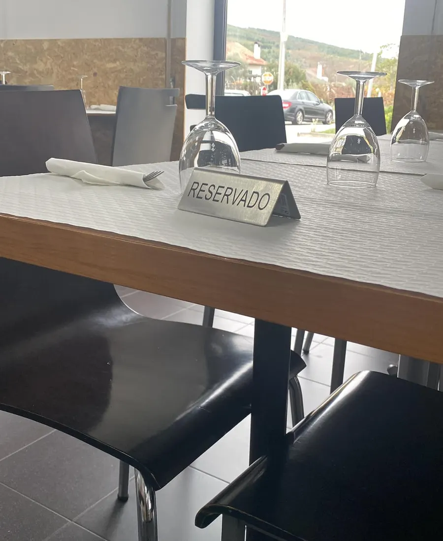 Uma mesa posta com a placa "Reservado" e a serra à janela